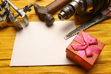 Father day or labor day concept background. Present gift box and work tool on the yellow workbench...
