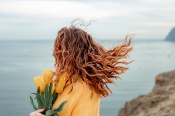 Portrait of a happy woman with hair flying in the wind against the backdrop of mountains and sea....