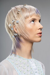 Young woman with a modern hairstyle, featuring delicate floral accessories and subtle purple...