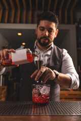 Professional bartender pouring a cocktail at bar