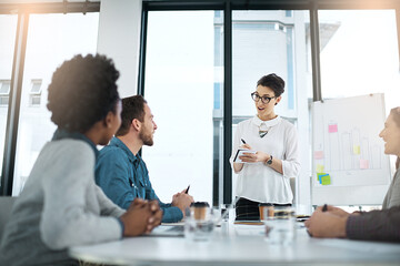 Team, woman and writing in meeting, office or boardroom for project as management for company or business. Group, presentation and whiteboard with sticky notes and graph for metrics in brainstorming