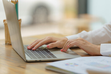 Close-up of woman's hands typing on a laptop.