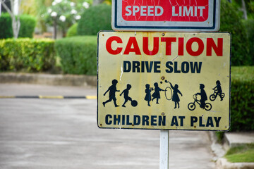 Sign caution speed limit drive slow children at play on yellow background at park in evening...