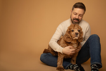 Studio portrait of a handsome caucasian man in his 40s sitting on the floor and embracing his...