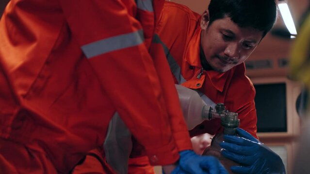 Asian man emergency medical technician (EMT) or paramedic nurse is performing CPR on a patient in an ambulance car