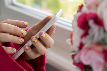 Woman manicured hands holding mobile phone, stylish summer colorful nails. Closeup of manicured...