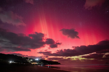 Aurora Australis at Muriwai Beach on 11 May, 2024. Crowd of people watching on the beach. Auckland.