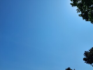 sky and clouds, A photo of an early summer blue sky in harmony with green trees 
