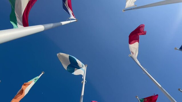 Flags of many countries waveing in the wind with blue sky from below