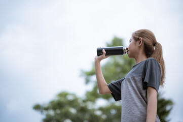 Sporty woman enjoying a drink of water in the park.