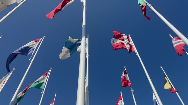Flags of many countries waveing in the wind with blue sky from below