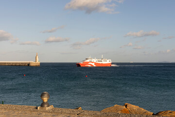 Ferry boat crossing Strait of Gibraltar in Tarifa harbor next to sacred heart of Jesus statue on a...
