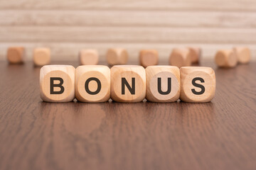 the text 'bonus' is written on wooden cubes on a brown background
