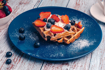 Breakfast dessert: Belgian waffles with strawberries and blueberries sprinkled with powdered sugar...