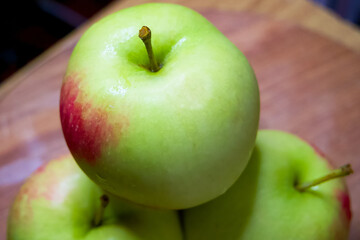 Organic Apple Display. Green apples, one in focus, on a rustic wood backdrop.