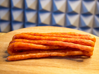 Sausages piled on a wooden surface, contrasting with a checkered backdrop. Ideal for showcasing in culinary presentations or grocery store promotions.