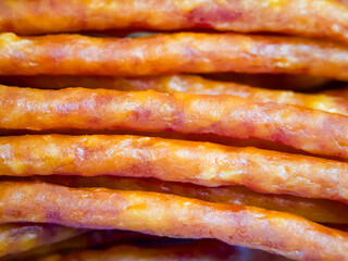 A close up of a row of meat sticks. The sticks are brown and have a slightly crispy texture....