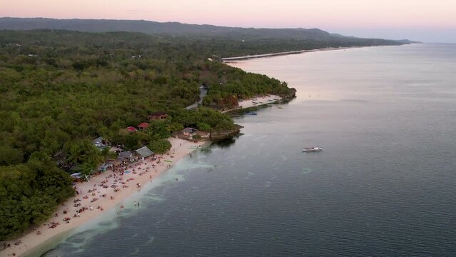 4K Aerial Drone video of beautiful sunset spot, Paliton beach at golden hour with people watching sunset, Siquijor island, Philippines