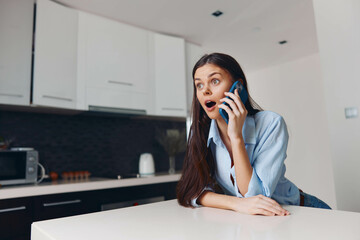 Woman using cell phone at kitchen table, casual conversation in modern home setting, technology and...