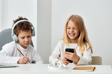 Happy siblings doing online homework together at home a boy and a girl sitting at a table in their...