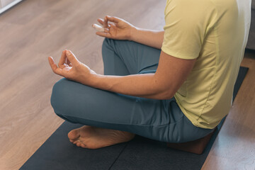 Guided Meditation at Home. Sporty man in active wear meditates on yoga block in living room.
