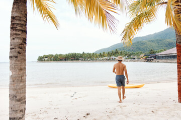 Happy Asian Man Kayaking on a Tropical Beach with a Colorful Canoe: Active Leisure and Enjoyment on...