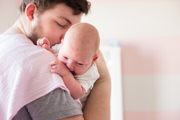 Young father burping a newborn baby girl after feeding
