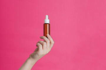 Serum brown glass bottle or essential oil with pipette on pink background. Natural Organic Spa...