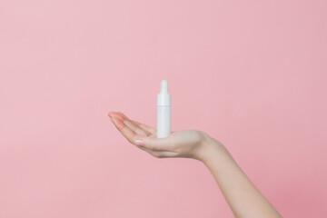Hand holds serum glass white bottle (essential oil) with pipette. Luxury product cosmetic...