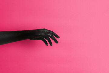 Black painted elegant woman's hand on her skin gesticulates on pink background. High Fashion art...