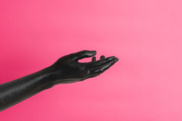 Black painted elegant woman's hand on her skin gesticulates on pink background. High Fashion art concept