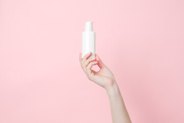 Hand holds white cream bottle with pump. Concept of beauty. Daily beauty product