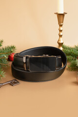 Rolled-up black fashionable men's leather belt with automatic buckle, Christmas fir tree, shiny...