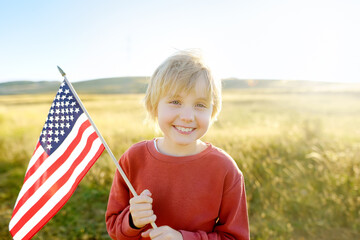 Cute little boy celebrating of July, 4 Independence Day of USA at sunny summer sunset. Child...