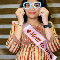 Obraz premium A pregnant Indian lady poses for outdoor pregnancy shoot and hands on belly, Indian pregnant woman puts her hand on her stomach with a maternity dress at society park, Pregnant outside maternity shoot