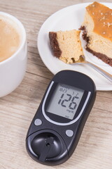 Glucose meter with high result sugar level, portion of sweet cheesecake and cup of coffee with...