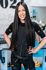 Beautiful young adult woman standing and posing in EMS suit after successful electro stimulation...