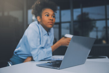 Bored young woman in the office working with a laptop and staring at computer screen