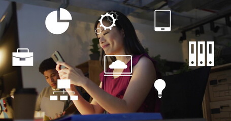 Image of computer application icons over asian businesswoman using smart phone in office