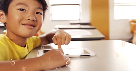 Image of multiple numbers over close of smiling asian boy using digital tablet in classroom - Powered by Adobe