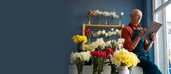 An elderly European male flower seller checks flower delivery.