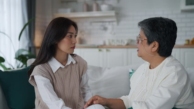 Middle-aged Asian mother listens to her daughter's problems and encourages her with love and care in Livingroom at home.
