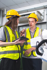 A Group of engineer are examining machine robot arm with smart tablet. Installation indoor industrial factory. Technician coworker check for repair maintenance electronic operation with remote system