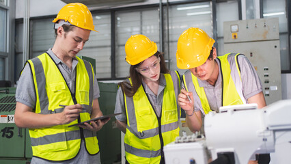 A Group of engineer are examining machine robot arm with smart tablet. Installation indoor...