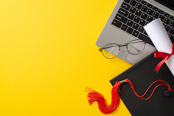Bright image featuring a graduation cap and diploma on top of a laptop, with glasses alongside, set...
