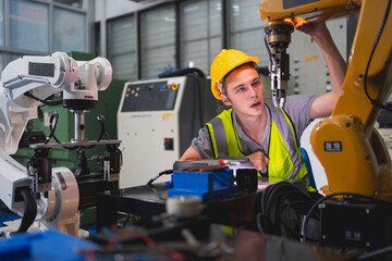 Professional and smart engineer is using his technical hard skill to fix, repair or maintenance machine robotic arm in factory or industrial, employee examining or welding automobile machine workshop