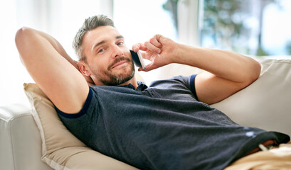 Portrait, man and couch on call with smartphone enjoying day off from work, talking and network on digital technology. Happy, male person and relaxing at home in lounge on cellphone to communicate