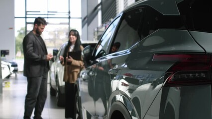 Bearded male buyer selects a car in a car dealership with the help of a car salesman. Concept of buying and selling a car, car rental and car service.
