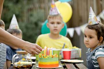 Cute funny nine year old boy celebrating his birthday with family or friends and eating homemade...