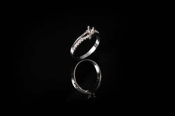 Silver ring with diamond isolated on black background with reflection.
